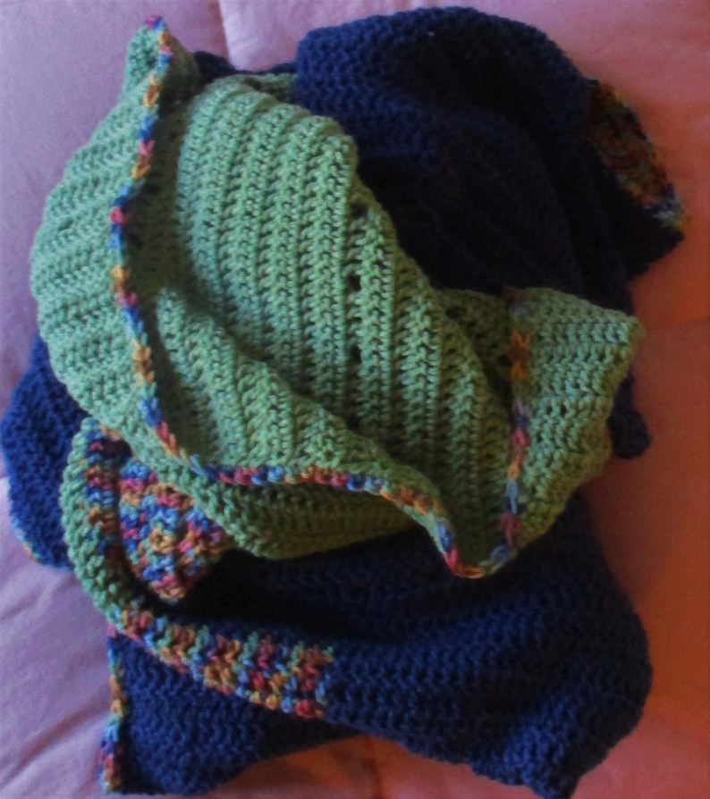 May include: A green and blue crocheted blanket with a colorful border. The blanket is folded in half and has a soft, textured appearance.
