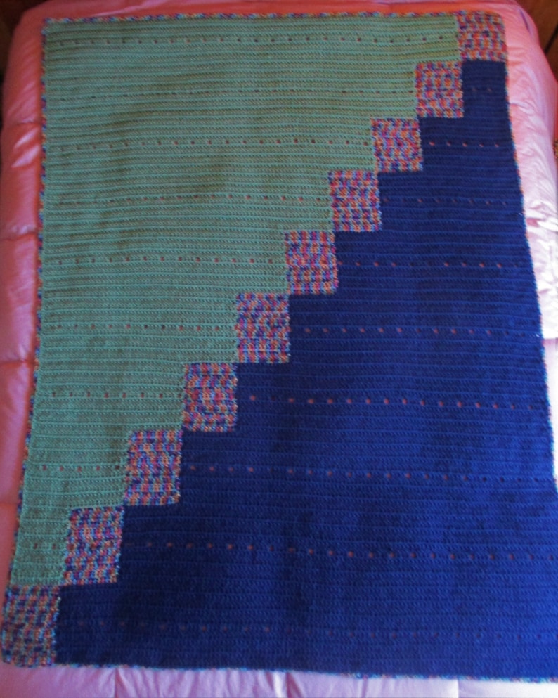 May include: A crocheted blanket with a diagonal pattern of blue and green squares. The squares are outlined in a multi-colored yarn.