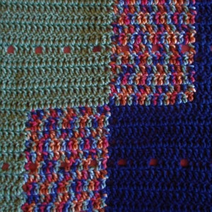 May include: A crocheted blanket with a blue, green, pink, and orange color scheme. The blanket is made of different colored squares.