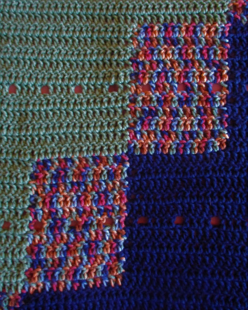 May include: A crocheted blanket with a blue, green, pink, and orange color scheme. The blanket is made of different colored squares.
