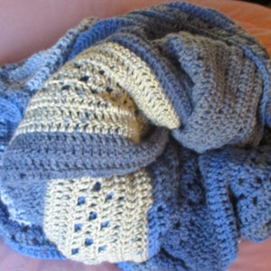 May include: A blue and white crocheted blanket with a textured pattern. The blanket is folded and appears soft and cozy.