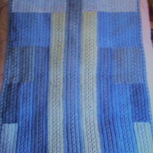 May include: A blue and white crocheted baby blanket with a geometric pattern.