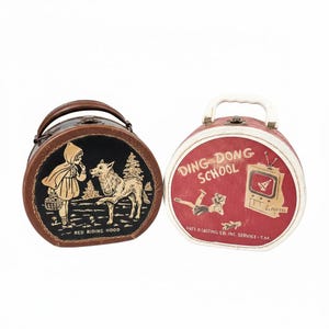 May include: Two vintage, round, handled cases. One features a Red Riding Hood illustration in gold on black, with text "RED RIDING HOOD". The other is red with "DING DONG SCHOOL" text and a TV graphic.