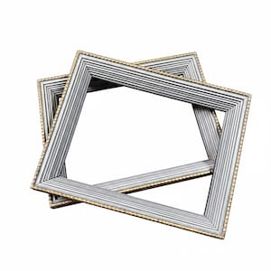 May include: Two silver picture frames with a gold trim are layered on top of each other. The frames have a ribbed texture and a rectangular shape. The frames are empty, ready to display photos or artwork.
