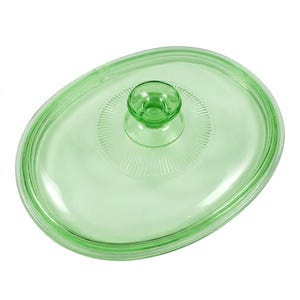 May include: An oval-shaped, light green glass lid featuring a central knob handle. The lid has a smooth, translucent surface with a decorative radial ribbed pattern surrounding the base of the knob, providing a clear view of the glass texture.