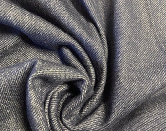 May include: Close-up of a dark blue denim fabric with a textured weave. The fabric is folded and draped, showing the soft texture and subtle sheen.
