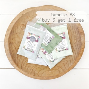 May include: A wooden bowl filled with five small bags of green and white powder paint. The bags are labeled with the names "sweetie jane", "in a pickle", "willow", "arb", and "par". The text "bundle #8 buy 5 get 1 free" is written above the bowl.