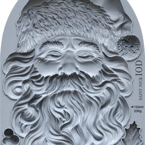 May include: A gray silicone mold featuring a detailed relief of Santa Claus's face, complete with a hat, beard, and closed eyes. The mold includes holly and berry accents, and the text "SAINT NICK IOD". Measurements are indicated in milliliters and grams.