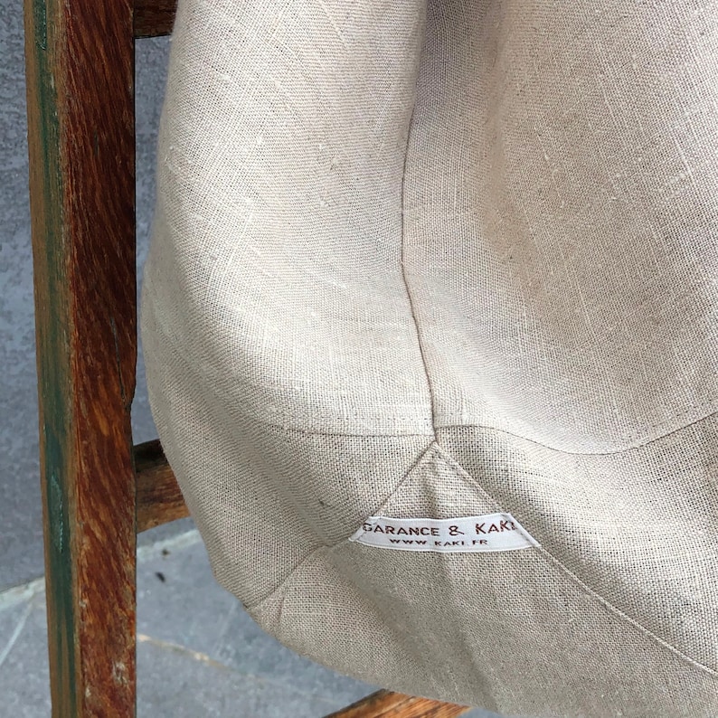 Puede incluir: Una bolsa de lona beige con una etiqueta marr&oacute;n que dice "Garance & Kaki" y "www.kaki.fr".