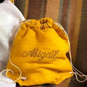 May include: A yellow drawstring bag with the name "Abigail" embroidered on the front.