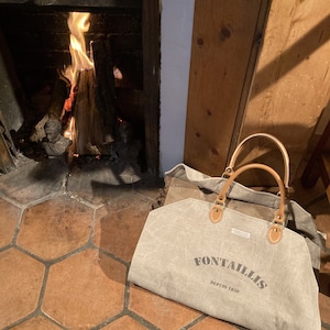 Peut inclure: Un sac fourre-tout en toile grise avec des anses en cuir marron et le texte "Fontaillis Depuis 1820" imprimé sur le devant.