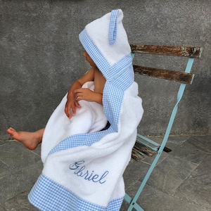 Könnte beinhalten: Weißes Kapuzenhandtuch mit blau-weißem Gingham-Besatz. Das Handtuch trägt den Namen "Gabriel" gestickt auf der Vorderseite.