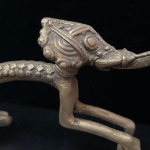 May include: A detailed bronze door handle in the shape of a mythical creature with a long snout and intricate details. The handle is designed to be used as a pull handle.
