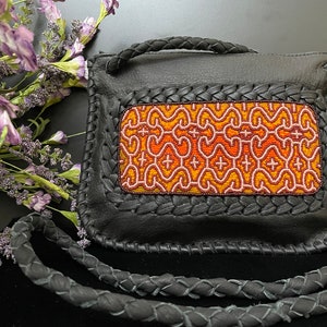 May include: A black leather crossbody bag with a braided strap and a colorful geometric pattern on the front flap.