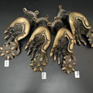 May include: Five antique brass hand-shaped door handles with floral accents. Each handle is numbered 1 through 5.