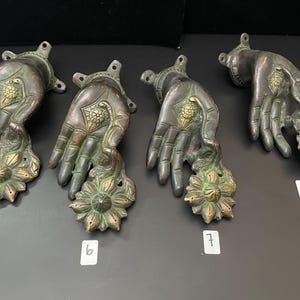 May include: Four ornate bronze door handles with a hand and flower design. The handles are numbered 5, 6, 7, and 8.