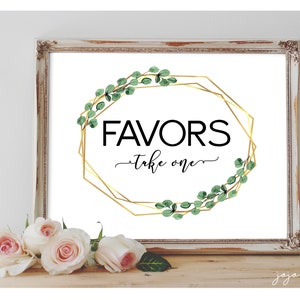 May include: A white sign with a gold geometric frame and green eucalyptus leaves around the frame. The sign says "Favors - Take One" in black text.