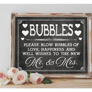 May include: A black chalkboard sign with white text that reads "BUBBLES" and "PLEASE BLOW BUBBLES OF LOVE, HAPPINESS AND WELL WISHES TO THE NEW Mr. & Mrs."