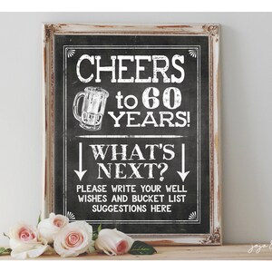 May include: A black chalkboard sign with white text that reads "Cheers to 60 Years! What's Next?" with a beer mug graphic. Below the text is a space for guests to write well wishes and bucket list suggestions.