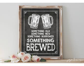 May include: A black chalkboard sign with a white wooden frame. The sign has a white chalk drawing of two beer mugs and the text "Something old, something new, something borrowed, something brewed".