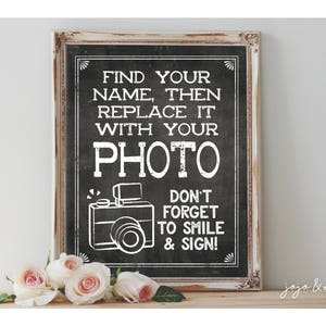 Puede incluir: Un letrero de pizarra enmarcado en blanco con texto negro que dice "Encuentra tu nombre, luego reemplázalo con tu foto. ¡No olvides sonreír y firmar!" Una ilustración en blanco y negro de una cámara está debajo del texto.
