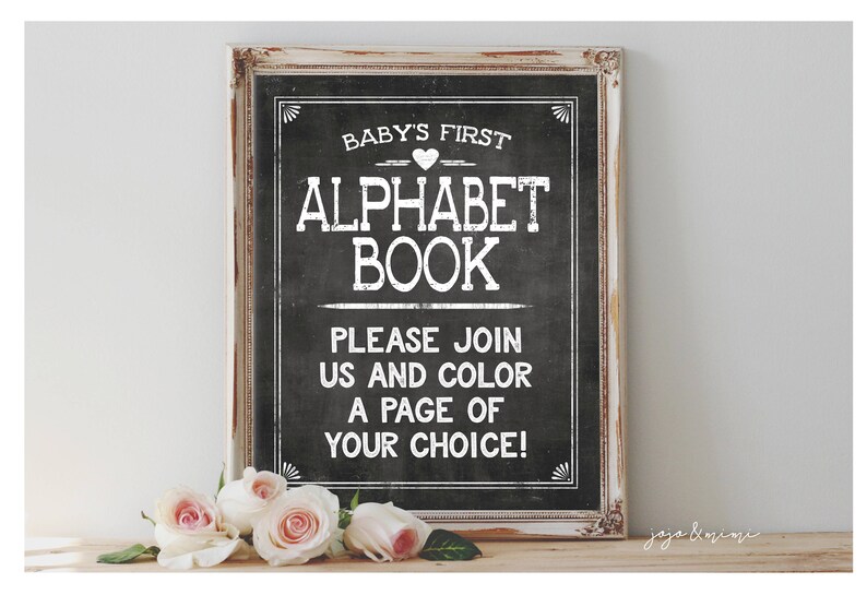 May include: A white sign with black lettering on a distressed wood frame. The sign says "Baby's First Alphabet Book" and "Please join us and color a page of your choice!"