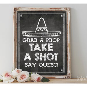 Può includere: Un cartello in ardesia nera con cornice bianca, che presenta un'illustrazione di sombrero e il testo "Prendi un accessorio, fai un shot, di' queso!"