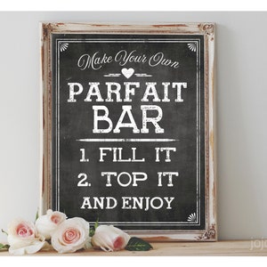 Puede incluir: Un letrero de pizarra enmarcado con el texto "Make Your Own Parfait Bar". El letrero tiene un marco blanco desgastado y está decorado con rosas blancas. Las instrucciones dicen "1. Fill It, 2. Top It, and Enjoy".