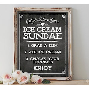 Peut inclure: Un panneau d'affichage en ardoise encadré de blanc avec du texte noir qui dit "Make Your Own Ice Cream Sundae" avec des instructions pour prendre un plat, ajouter de la crème glacée, choisir des garnitures et déguster. Le panneau est posé sur une surface en bois avec des roses roses devant.