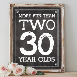 Puede incluir: Un letrero de pizarra enmarcado en blanco con fondo negro y texto blanco que dice "More Fun Than Two 30 Year Olds".