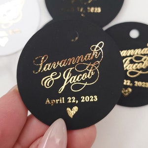 Può includere: Etichette rotonde nere per matrimoni con lettering dorato. Le etichette recitano "Savannah & Jacob" e "April 22, 2023".