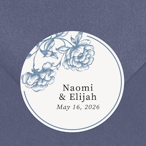 Puede incluir: Una pegatina redonda con un diseño floral azul y blanco, con los nombres "Naomi & Elijah" y la fecha "16 de mayo de 2026". La pegatina está colocada en un sobre azul.