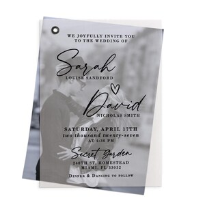 May include: A rectangular, semi-transparent wedding invitation card featuring a black and white photograph of a couple. The text reads: We joyfully invite you to the wedding of Sarah Louise Sandford and David Nicholas Smith, Saturday, April 17th, two thousand twenty-seven at 4:30 PM, Secret Garden, 248th St, Homestead, FL 33032, dinner and dancing to follow.