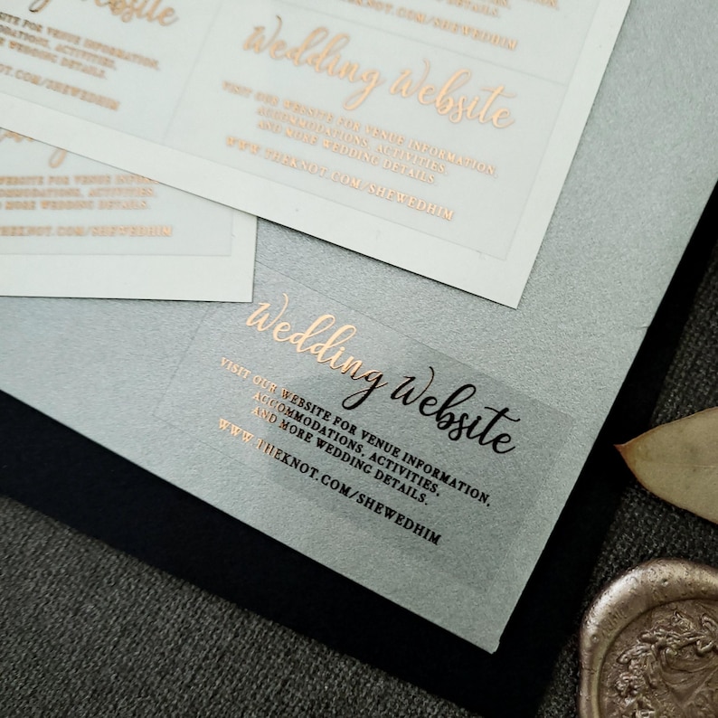 Transparent sticker with gold foiled text print.  Wedding Website is written at the top. Below the text reads: visit our website for venue information, accommodation, activities, and more wedding details. At the bottom is your wedding website link.