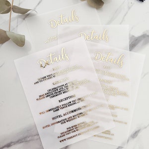 Op de afbeelding: Vier doorschijnende witte kaarten met gouden letters die "Details" lezen. De kaarten bevatten informatie over een huwelijksceremonie en een receptie, inclusief datum, tijd en locatie. RSVP-informatie is ook inbegrepen.