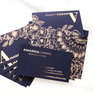 Black velvet business cards with a gold foil print. The design features gold floral decoration as a background. At the bottom in gold foiled print is written your name or business name. At the back the card is black with your personal details in gold