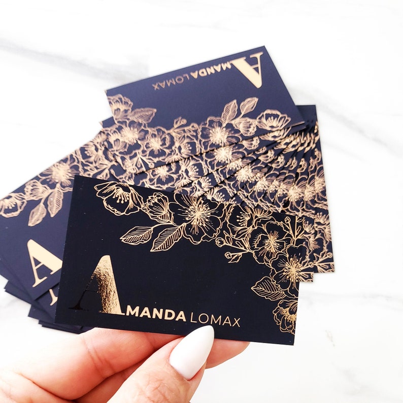 Black velvet business cards with a gold foil print. The design features gold floral decoration as a background. At the bottom in gold foiled print is written your name or business name.