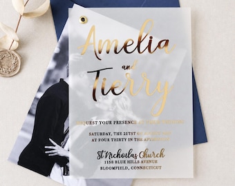 Op de afbeelding: Een doorschijnende, mat acryl huwelijksuitnodiging met goudfolie belettering: Amelia and Tierry, request your presence at their wedding, Saturday, the 21st of August 2021 at four thirty in the afternoon, St Nicholas Church, 1158 Blue Hills Avenue, Bloomfield, Connecticut.