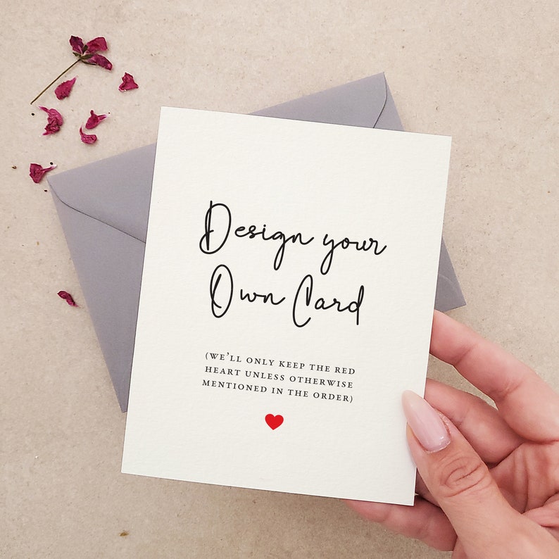 May include: A white card with black text that reads "Design your Own Card (WE'LL ONLY KEEP THE RED HEART UNLESS OTHERWISE MENTIONED IN THE ORDER)". A small red heart is below the text.
