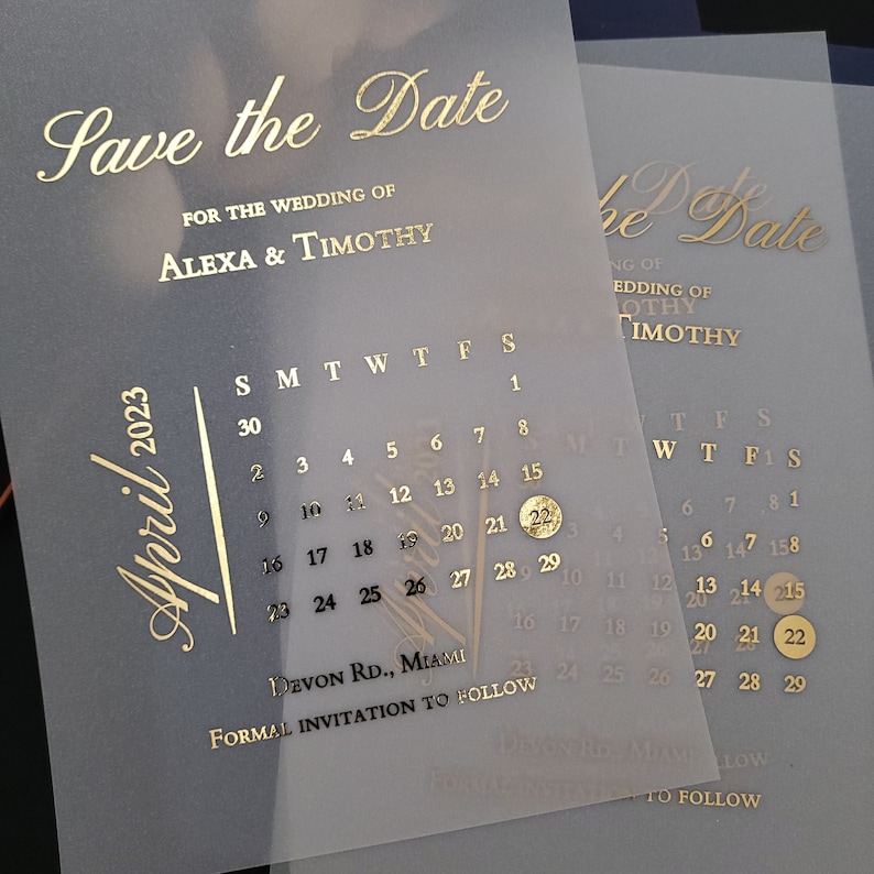 May include: Gold foil save the date card with a calendar showing April 2023 with the 21st circled. The text reads "Save the Date" for the wedding of Alexa & Timothy. The bottom of the card reads "Devon Rd., Miami" and "Formal Invitation to Follow."