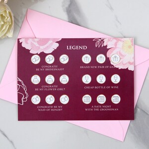May include: A burgundy card with a floral design and a legend for a bridal shower game. The legend includes icons for a bridesmaid, flower girl, maid of honour, a new pair of garters, a bottle of wine, and a date night with the groomsman.