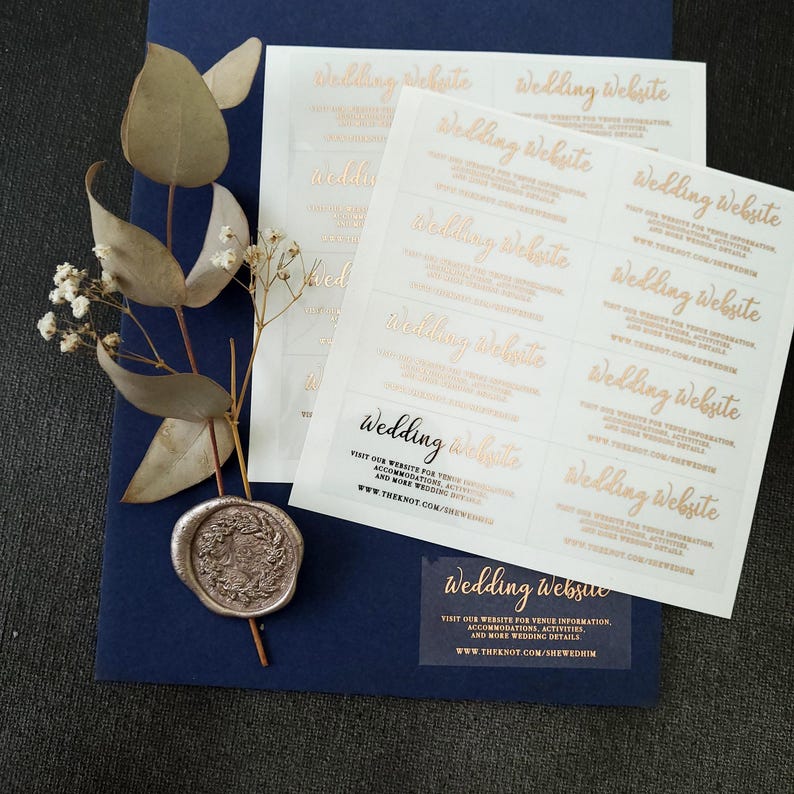 Transparent sticker with gold foiled text print. The design features hand-lettered typography spelling out Wedding Website at the top. Below the text reads: visit our website for venue information, accommodation, activities, and mre wedding details.