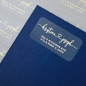 Etiquetas de remetente personalizadas para envelopes e convites de casamento com corações transparentes em folha de ouro e nomes interligados.