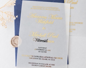 Op de afbeelding: Een doorschijnende trouwkaart van kalkpapier met goudfolie belettering, geplaatst op een donkerblauwe envelop. De tekst luidt: The honor of your presence is requested at the marriage of Arianna Maria Withfield to Mitchell Paul Vitresilvan.