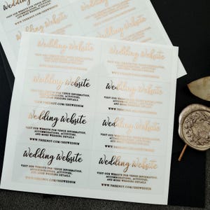 Transparent sticker with gold foiled text print.  Wedding Website is written at the top. Below the text reads: visit our website for venue information, accommodation, activities, and more wedding details. At the bottom is your wedding website link.