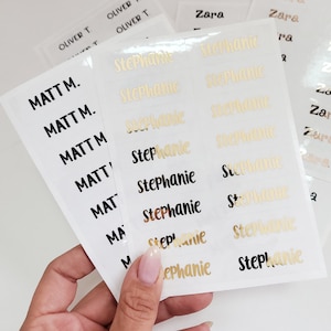 May include: A sheet of white labels with gold and black lettering. The labels are for names, including "Matt M." and "Stephanie".