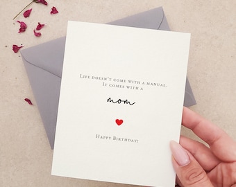May include: A white card with the text "LIFE DOESN'T COME WITH A MANUAL. IT COMES WITH A mom" and a red heart. The text "HAPPY BIRTHDAY!" is at the bottom of the card.