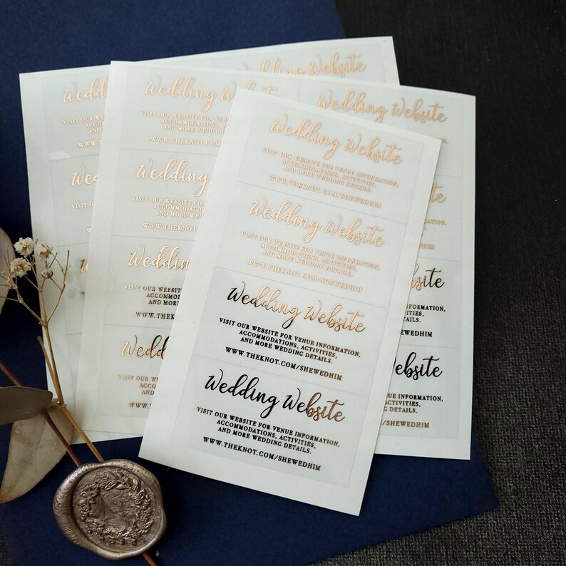 Transparent sticker with gold foiled text print. The design features hand-lettered typography spelling out Wedding Website at the top. Below the text reads: visit our website for venue information, accommodation, activities, and mre wedding details.