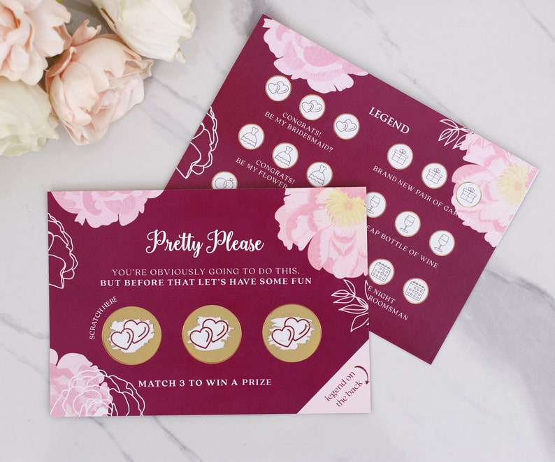 May include: A pink and burgundy card with a floral design. The card has three gold circles with hearts inside. The text on the card reads "Pretty Please You're obviously going to do this. But before that let's have some fun. Scratch here Match 3 to win a prize Legend on the back".