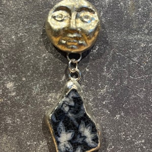 May include: A silver chain necklace with a gold face pendant and a black and white stone pendant.